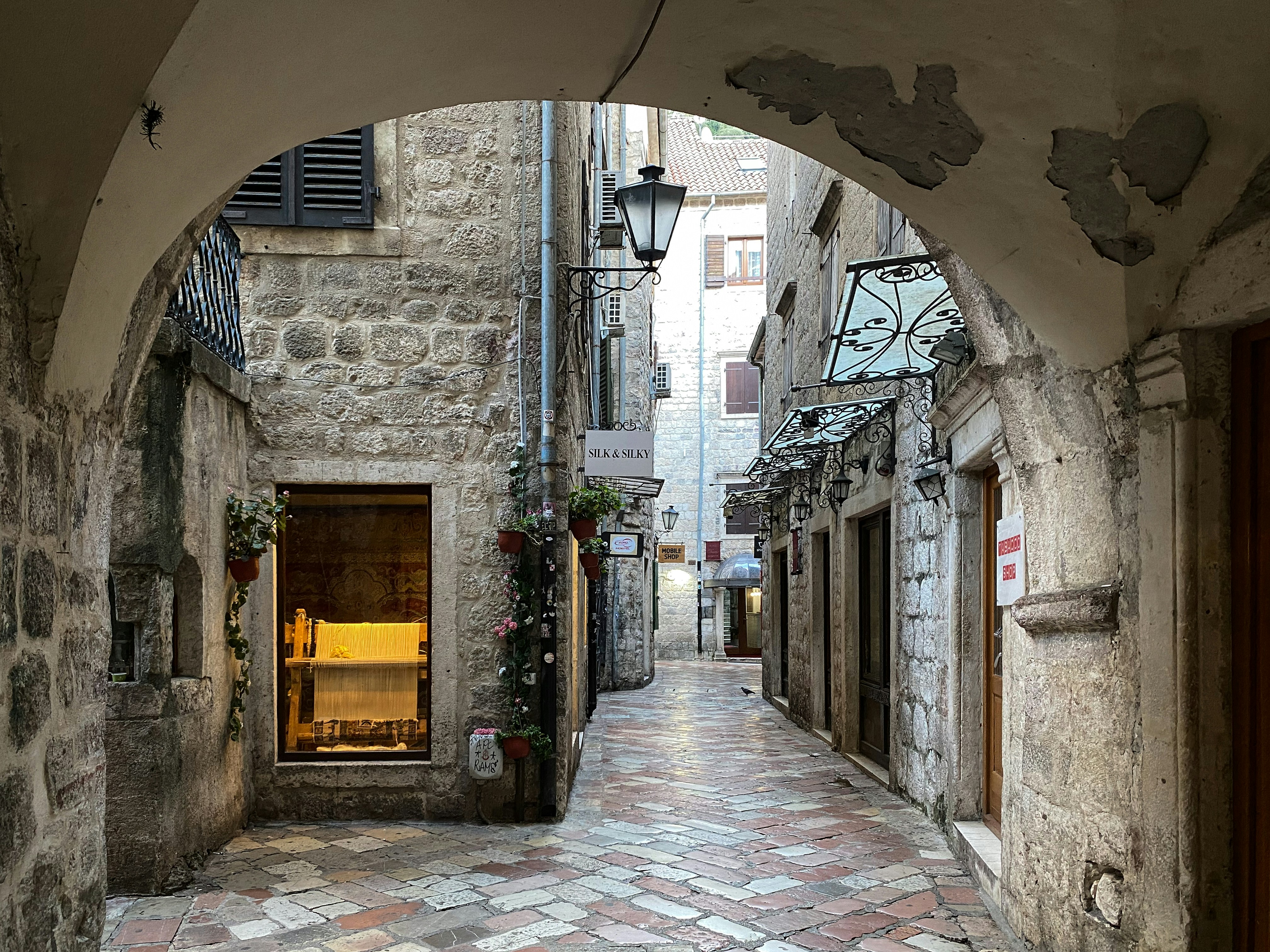 a cobblestone street with an arched doorway, Old Town Kotor on a Sunday morning