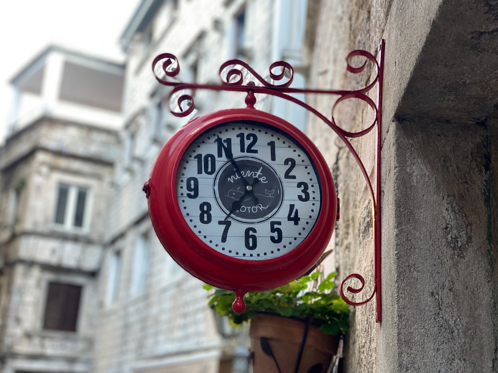 a red clock hanging from the side of a building