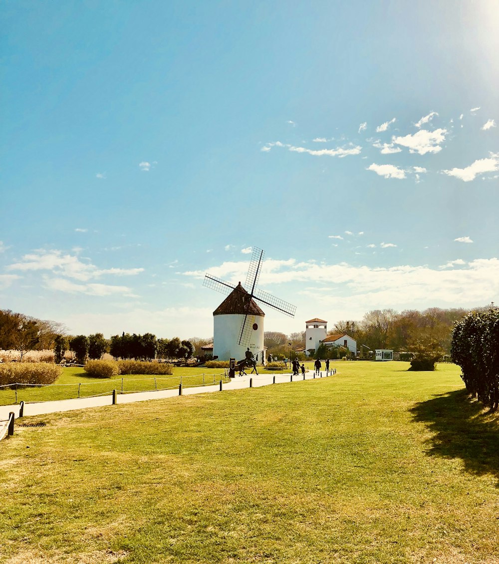 a group of people walking down a path next to a windmill