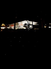 A gas station convenience store entrance framed by green plants and arched architectural details.