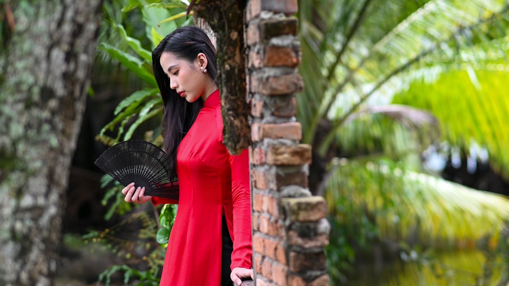 una mujer con un vestido rojo sosteniendo un abanico negro