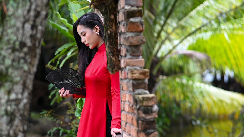 a woman in a red dress holding a black fan