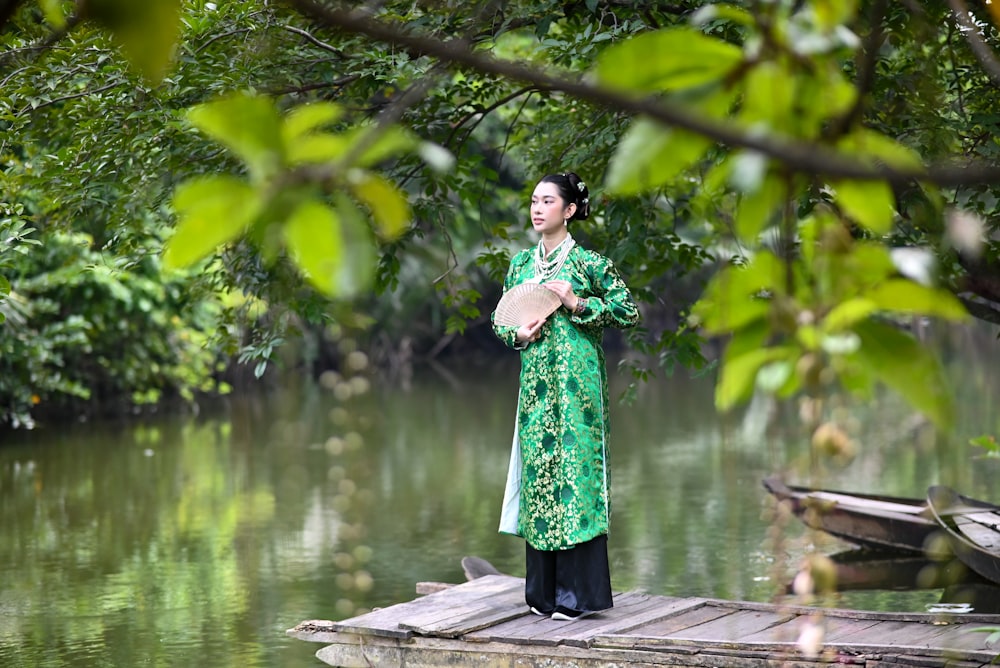 a woman in a green dress standing on a dock