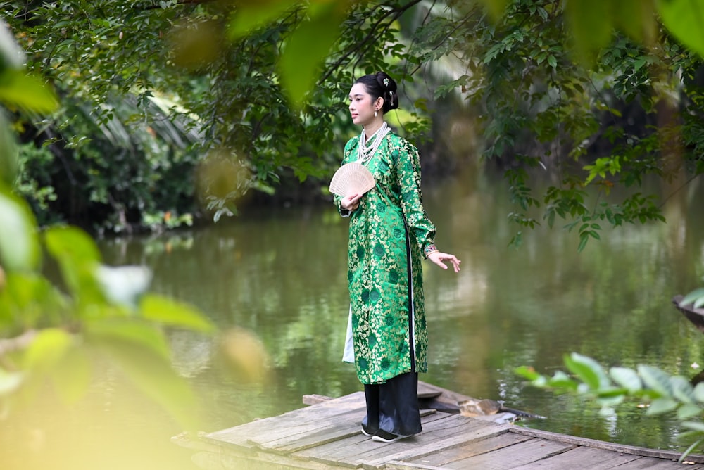 a woman in a green dress standing on a dock