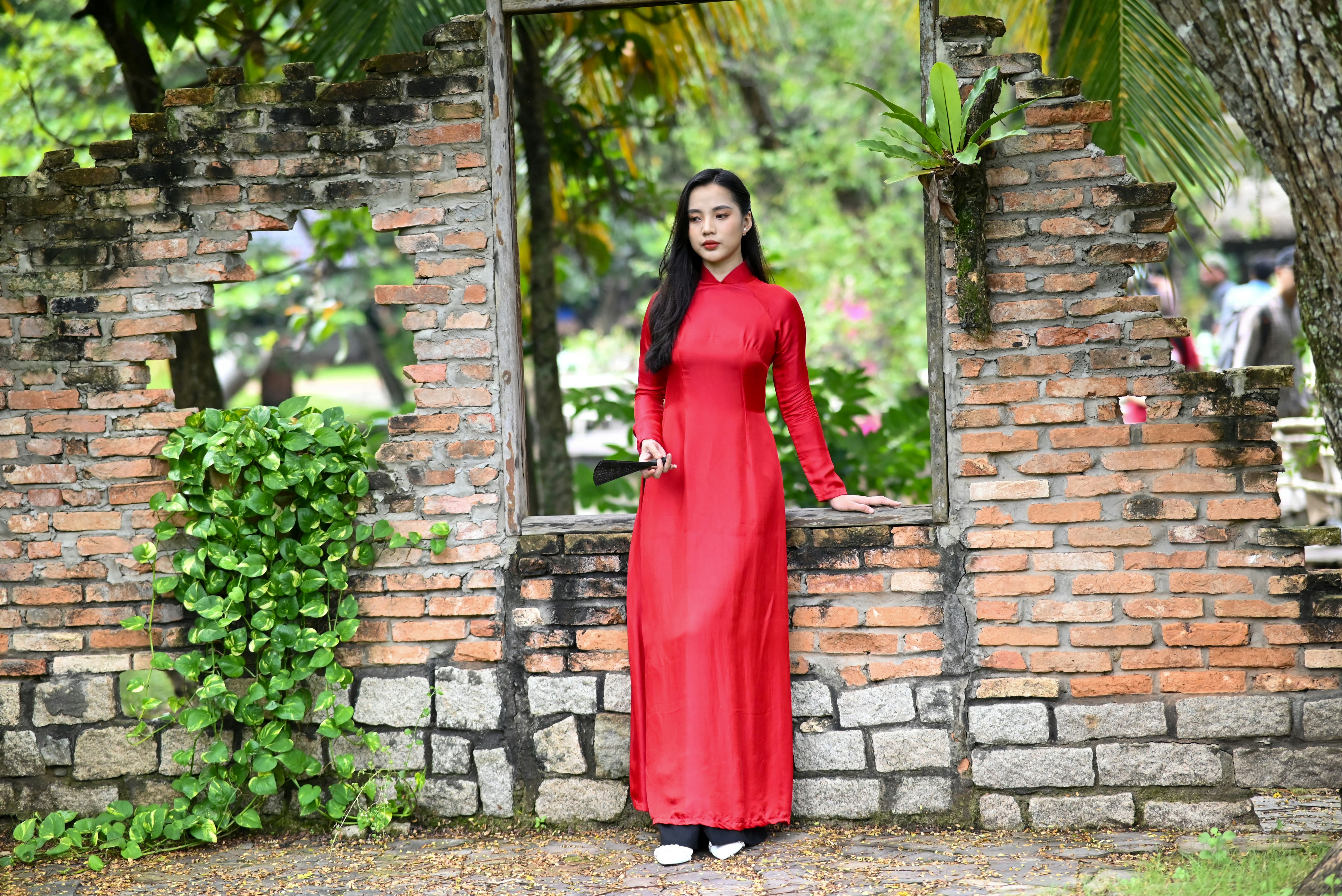 a woman in a red dress standing in front of a brick wall