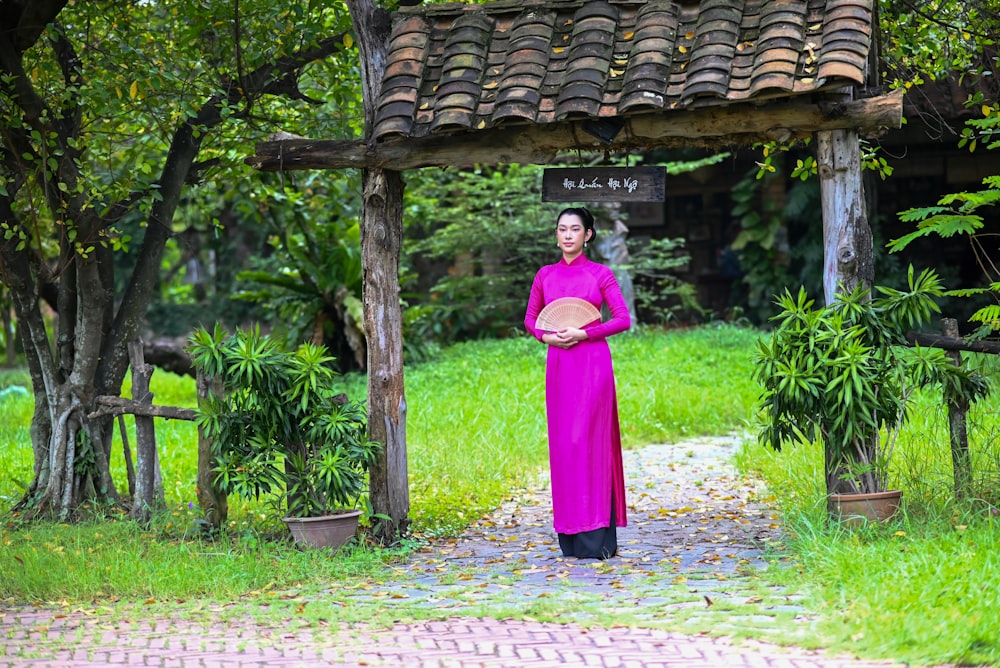 Una mujer con un vestido morado de pie frente a una glorieta