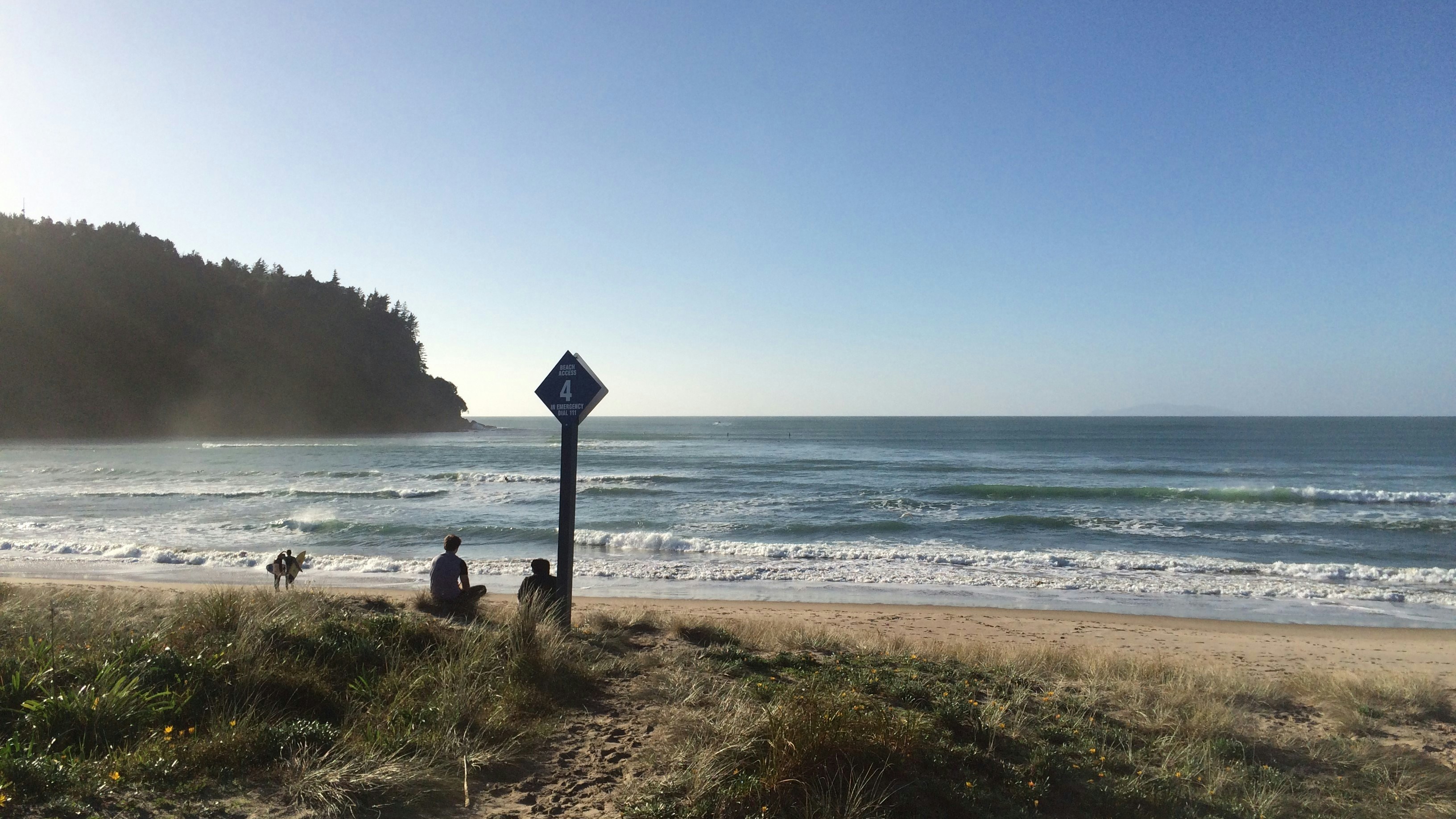 a couple of people standing on top of a sandy beach
