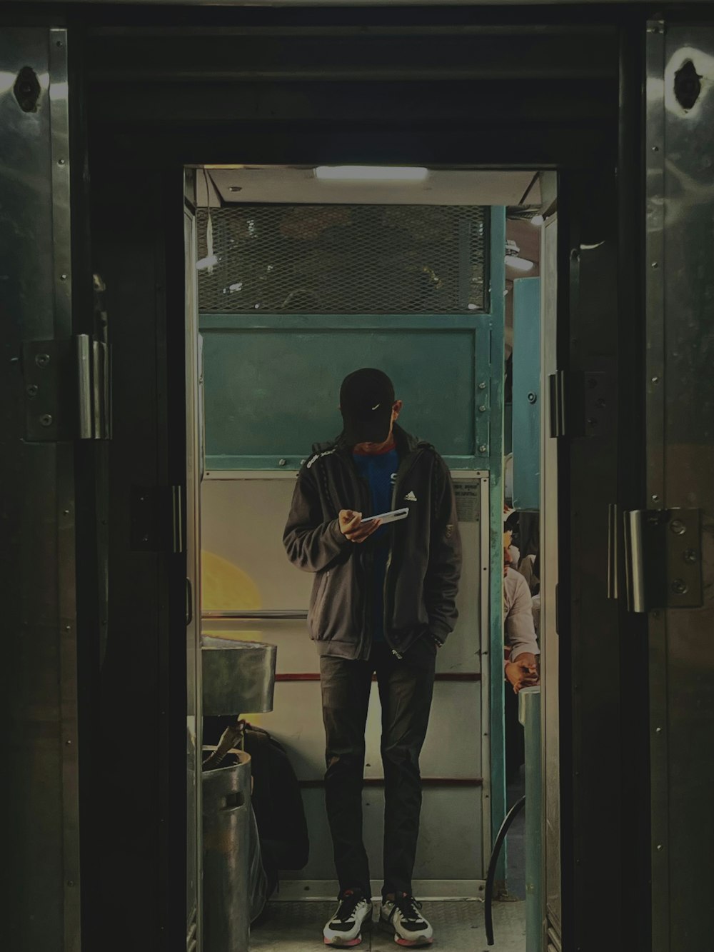 a man standing on a train looking at his cell phone