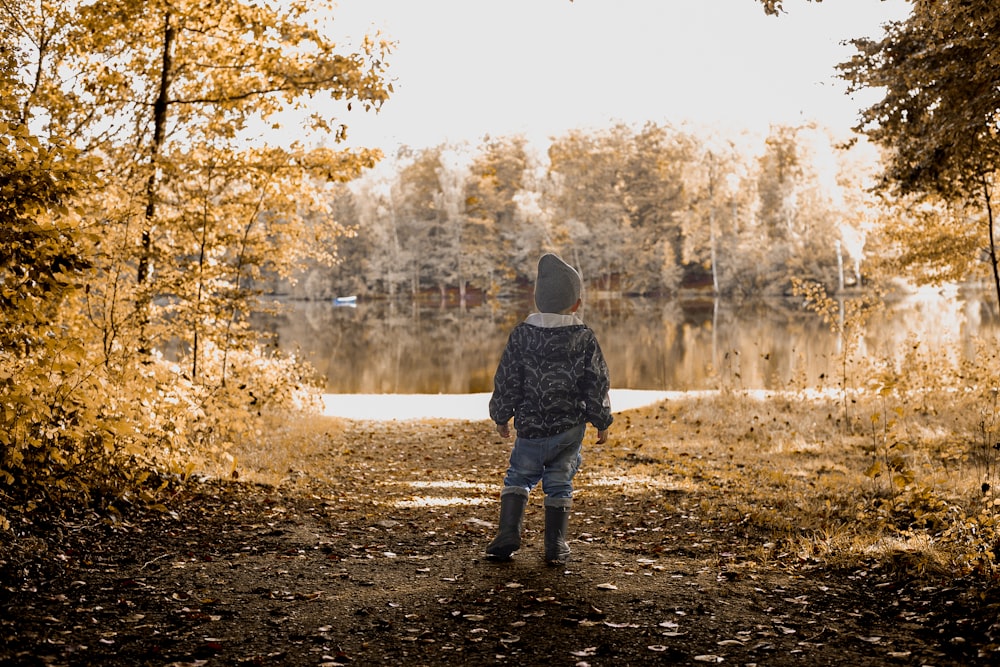 a young boy standing on a path near a body of water