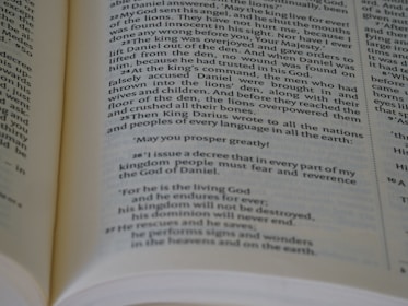 An open book featuring a section of text that appears to be a passage from a religious or biblical text, printed in a clear, serif font on off-white paper. The pages are slightly curved, suggesting that the book is laid open flat.