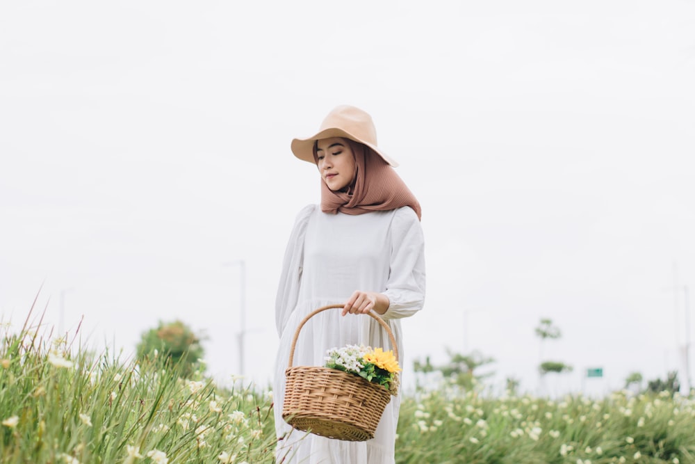 a woman in a white dress and hat holding a basket