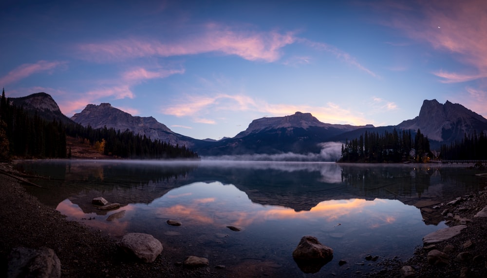 a lake surrounded by mountains under a cloudy sky