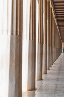 Rows of classical columns with gold accents, casting long shadows over polished marble floors.