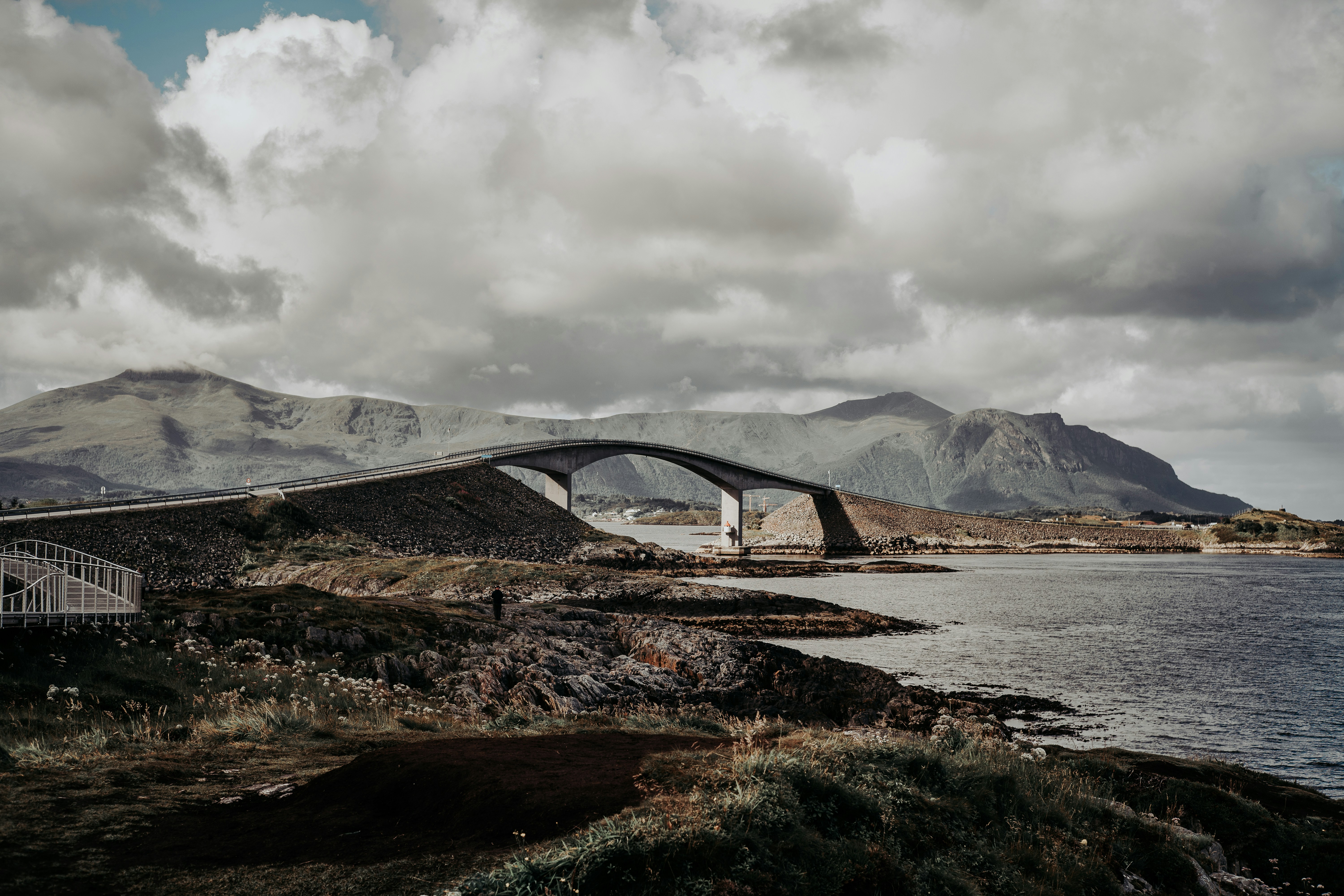 A bridge over a body of water with mountains in the background photo ...