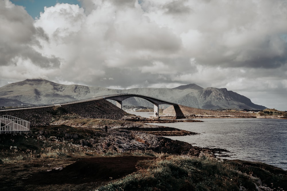 a bridge over a body of water with mountains in the background