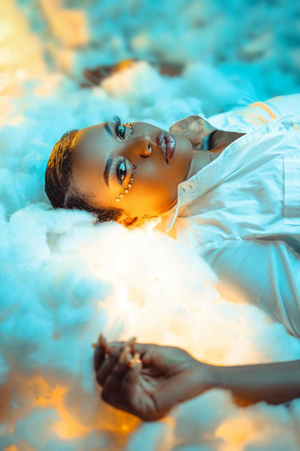 a woman laying on top of a cloud of white feathers