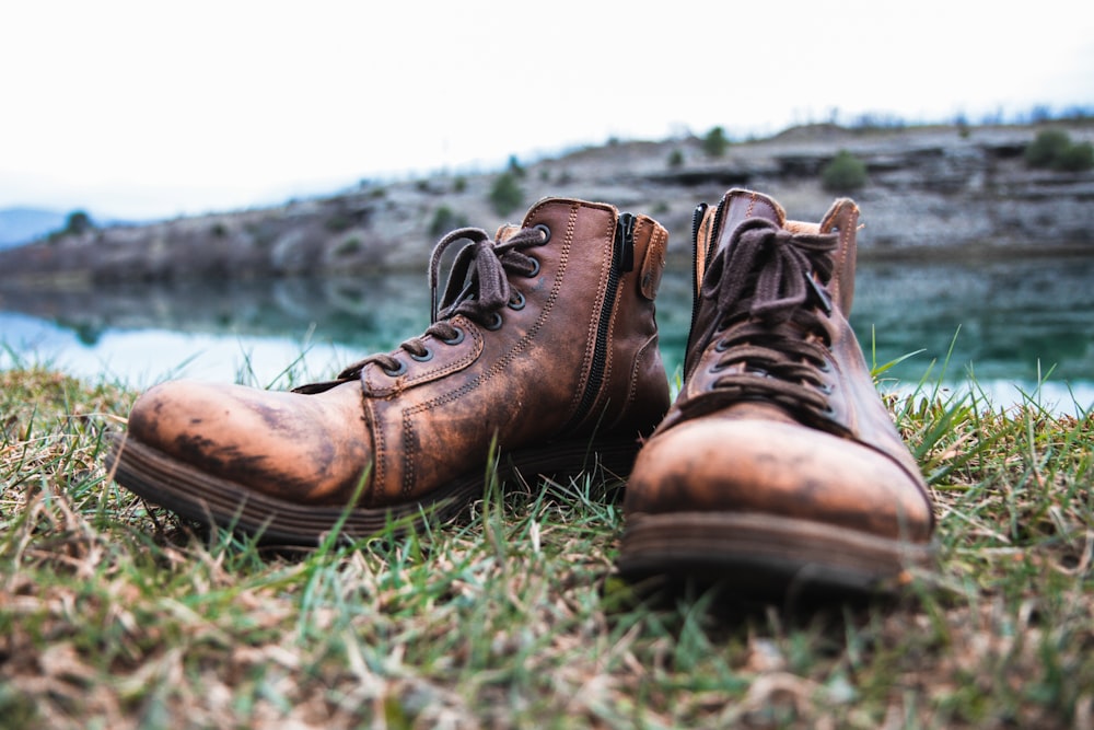 a pair of brown boots sitting on top of a grass covered field