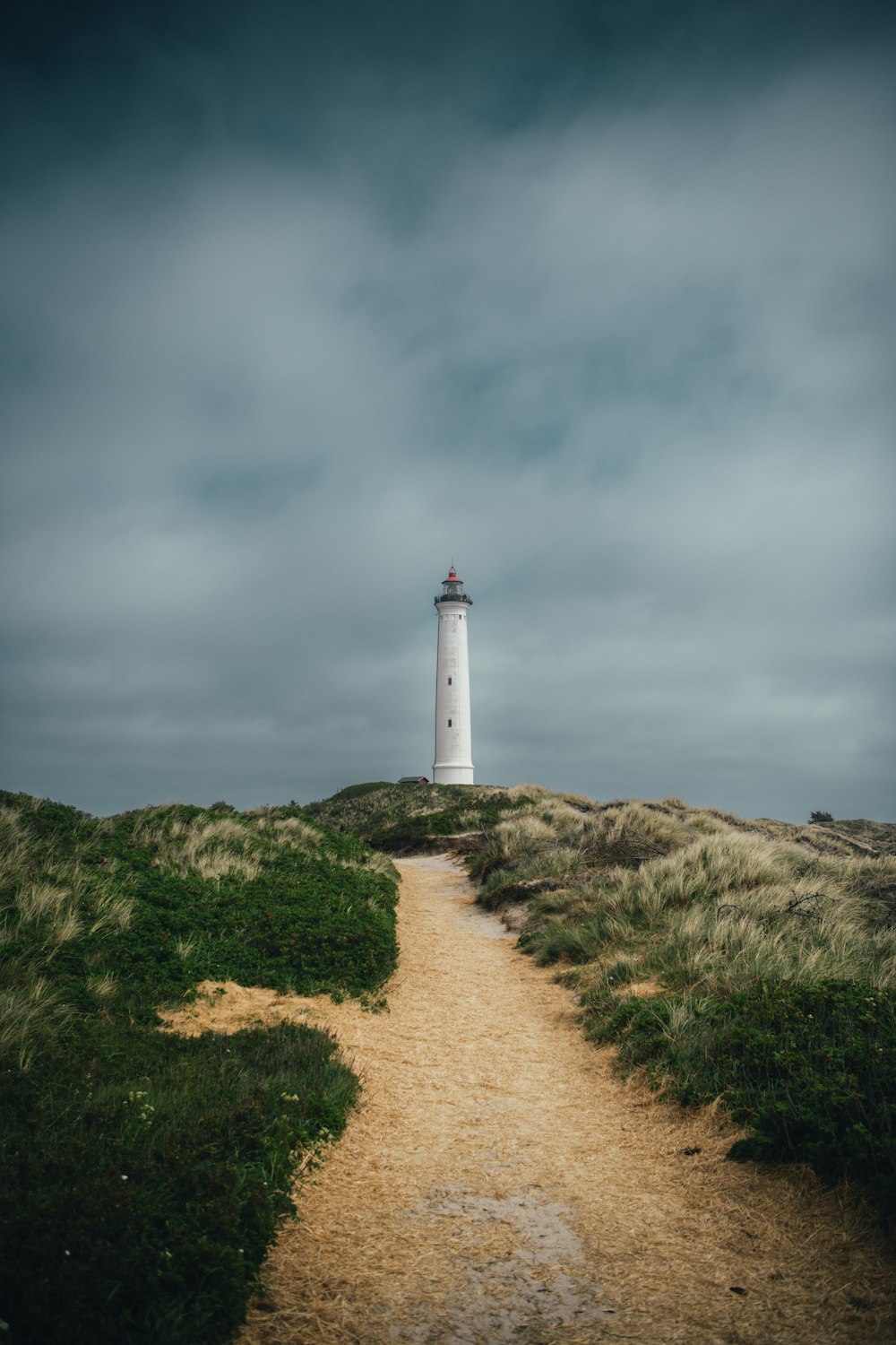 a path leading to a lighthouse on a cloudy day
