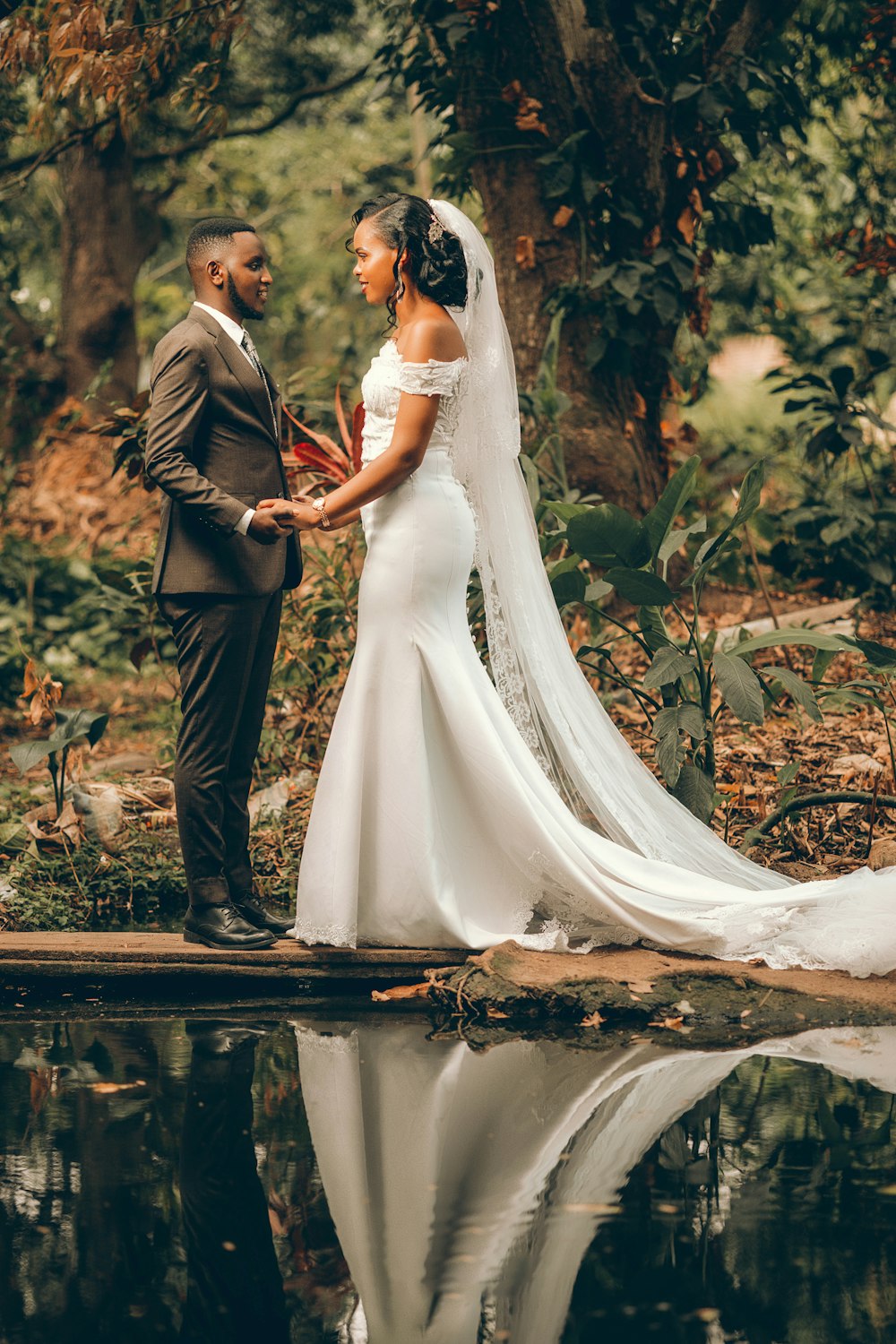a bride and groom standing on a dock in the woods