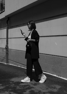 a woman walking down a street while holding a cell phone