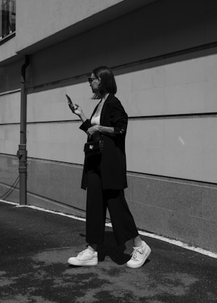 a woman walking down a street while holding a cell phone