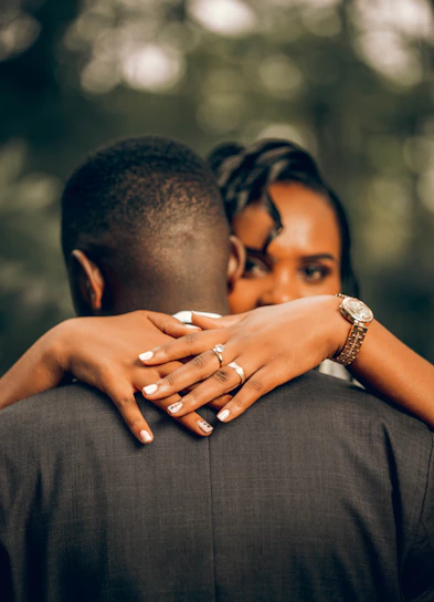 a couple embracing each other in front of trees