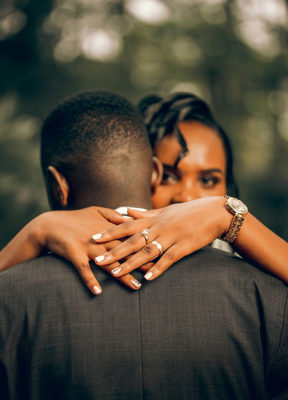 a couple embracing each other in front of trees