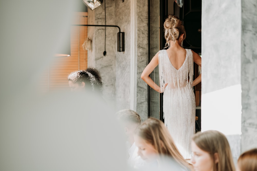 a woman in a white dress standing in front of a mirror