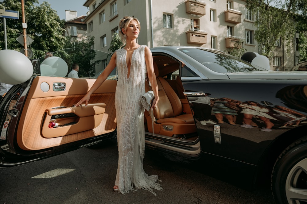 a woman standing next to a black car