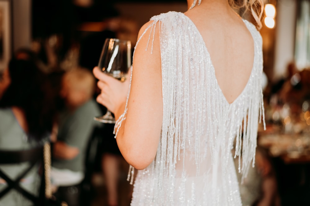 una donna in abito bianco che tiene in mano un bicchiere di vino