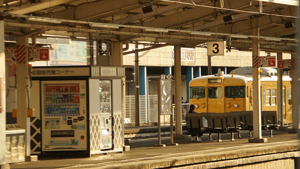 a yellow train traveling down train tracks next to a train station