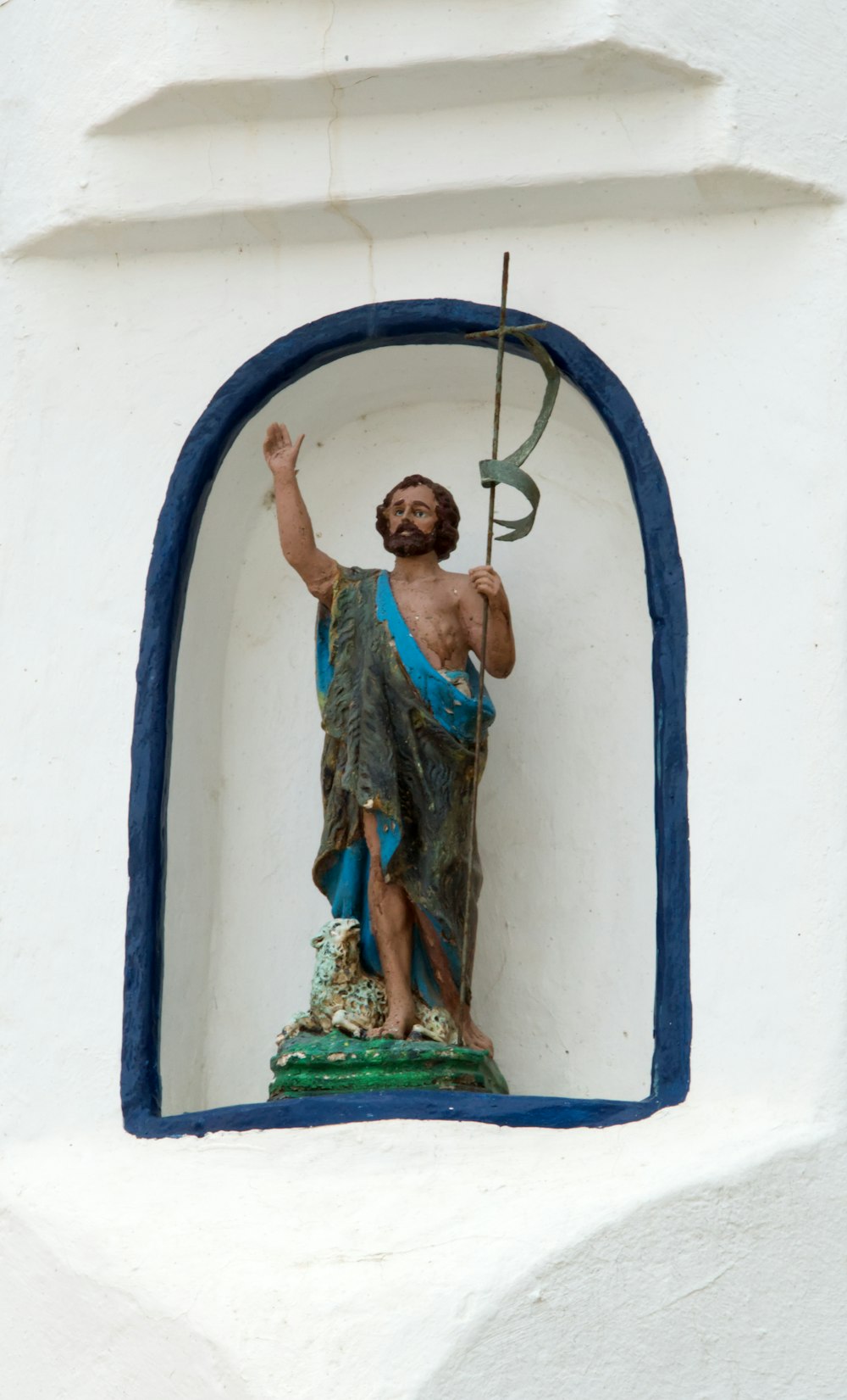 a statue of jesus holding a cross in a window
