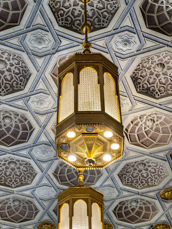 An architectural detail of a warm glowing pendant light against a black ceiling.