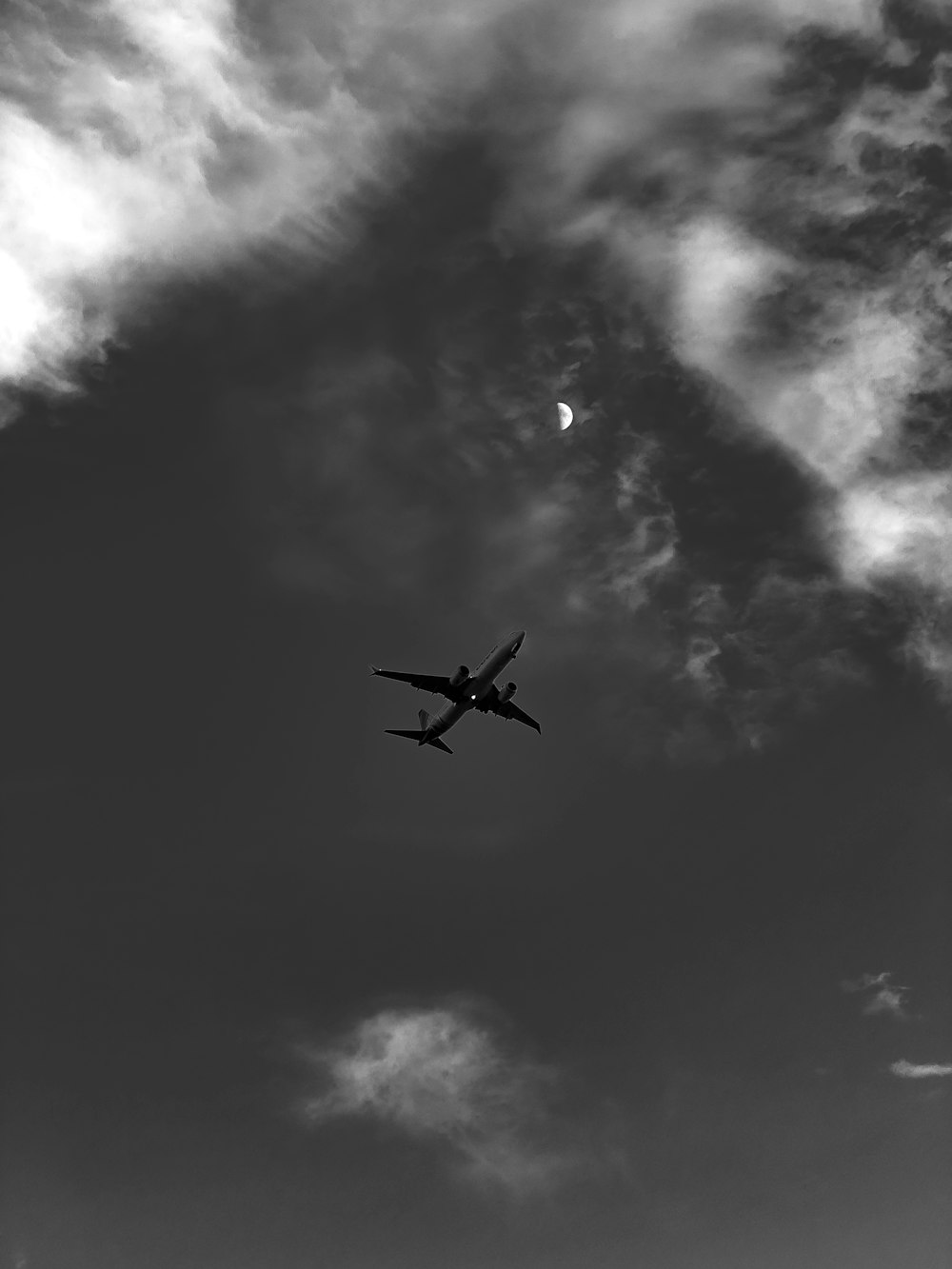 an airplane flying in the sky with a half moon in the background