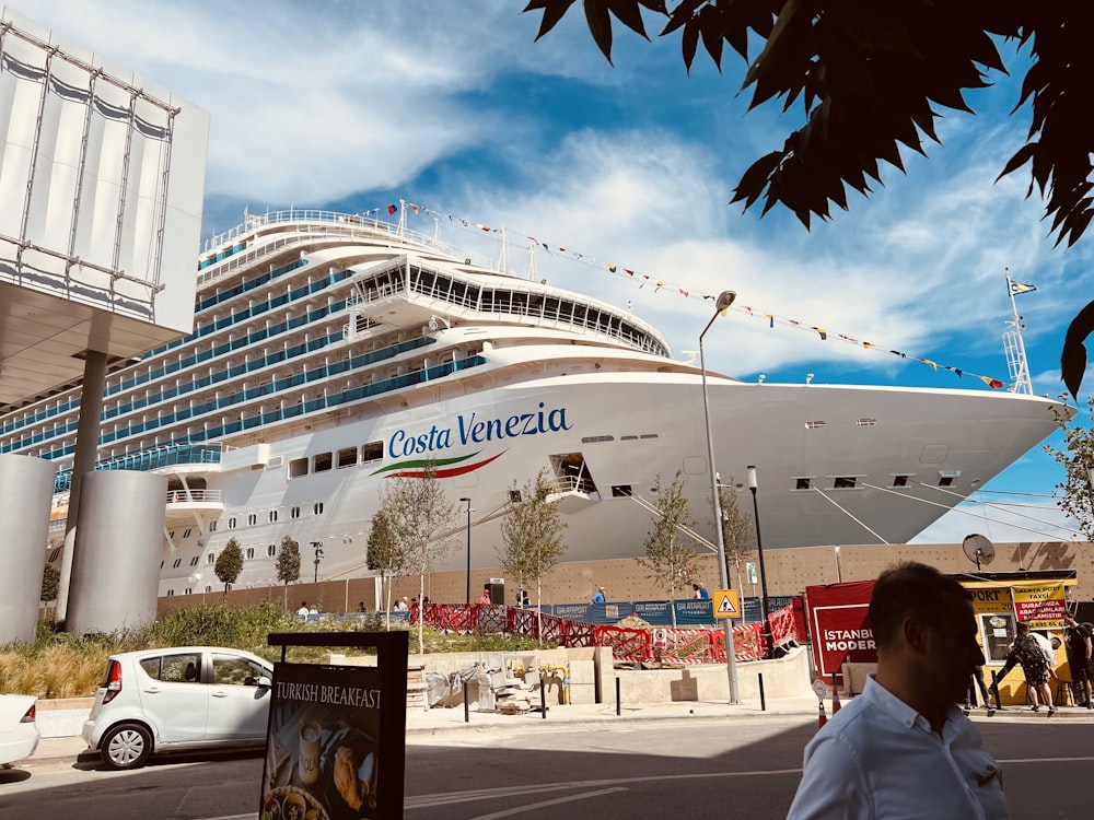 a cruise ship docked at a port with people walking around