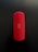 A red cylindrical Bluetooth speaker with a mesh texture, featuring control buttons for power, volume, and wireless connectivity in the center. The speaker is placed vertically against a dark background.