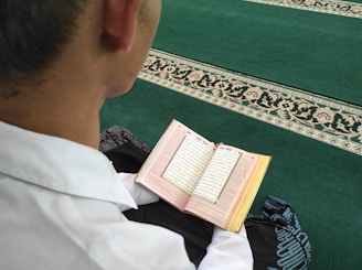 A student reflecting thoughtfully while reading a theological text at home.