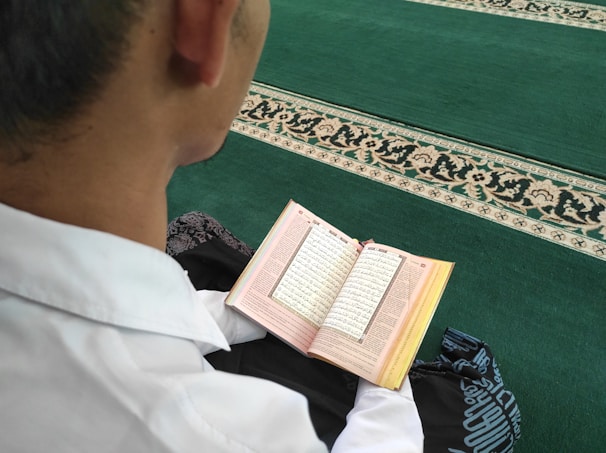 A student reflecting thoughtfully while reading a theological text at home.