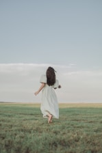 A sunlit field with a model wearing a flowing bohemian dress, barefoot and carefree.