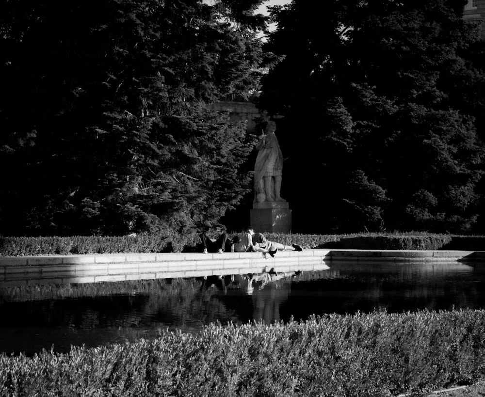 a black and white photo of a pond and a statue