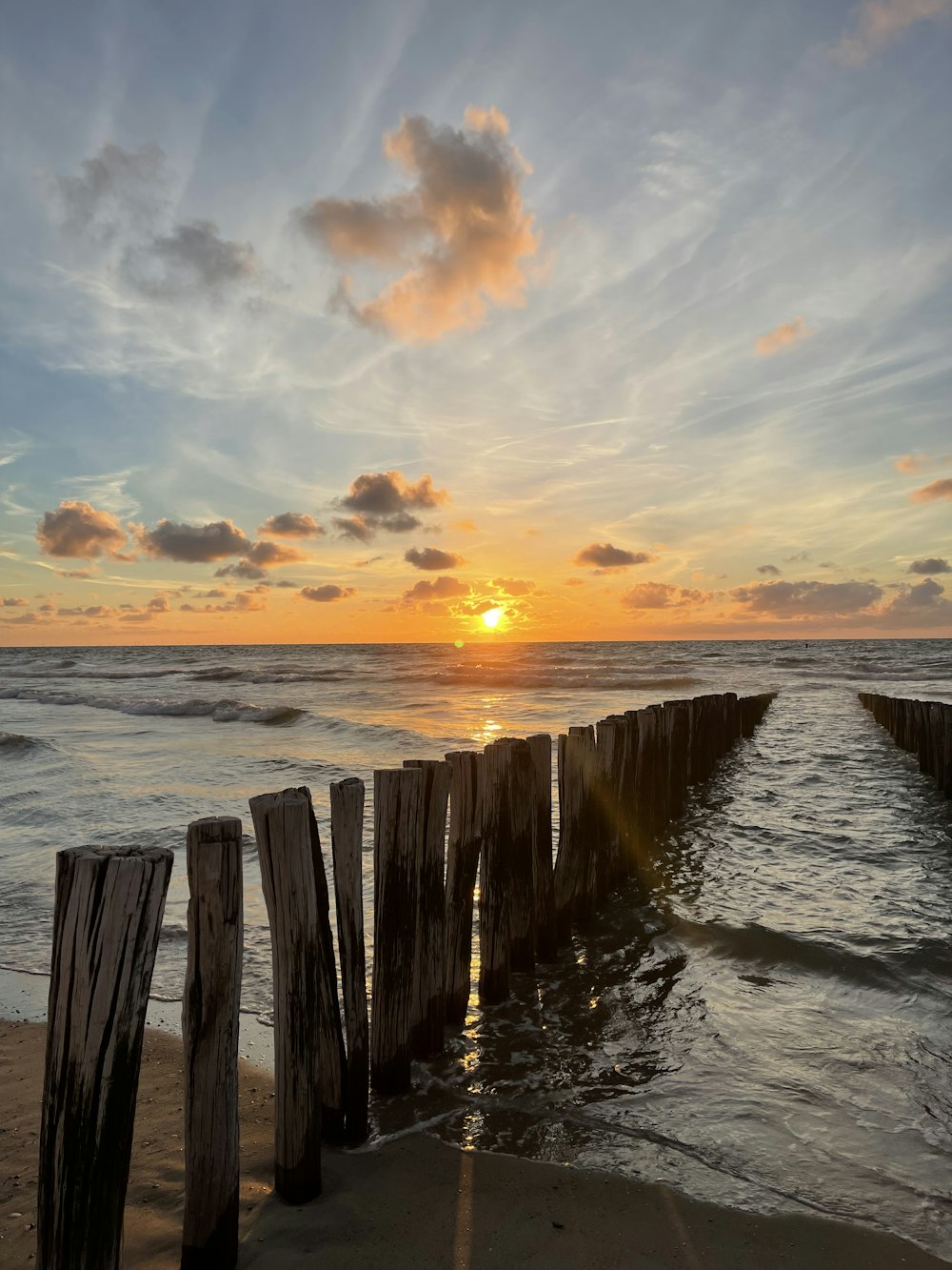 the sun is setting over the water at the beach