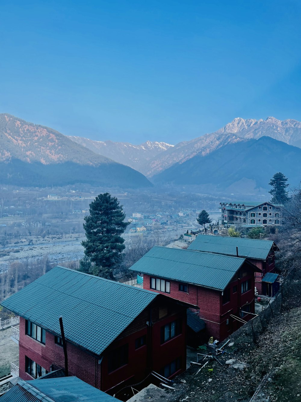 a red building with a green roof and mountains in the background