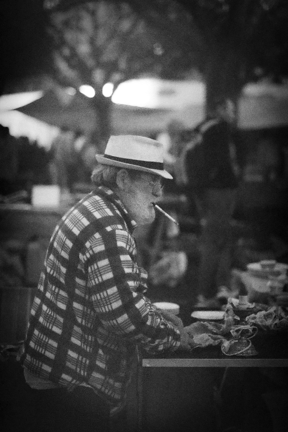 a man sitting at a table with a cigarette in his mouth