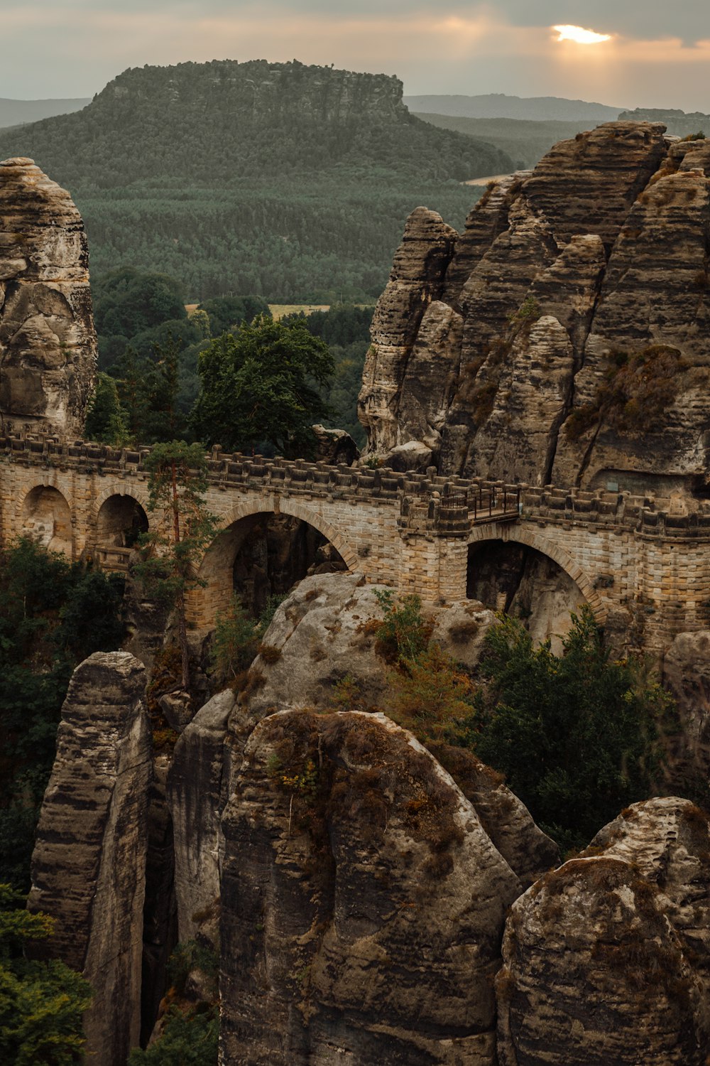 a stone bridge over a river surrounded by mountains