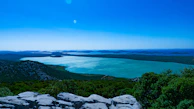 A panoramic view of the lagoon with reflections of the sky and distant hills.