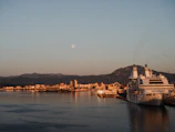 A serene sunrise over a luxury cruise ship docked at a bustling Mediterranean port.