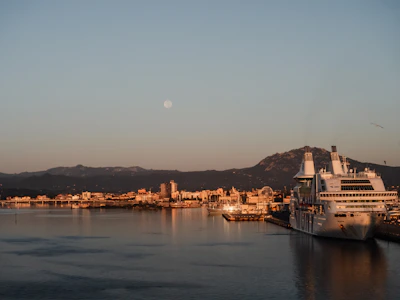 A serene sunrise over a luxury cruise ship docked at a bustling Mediterranean port.