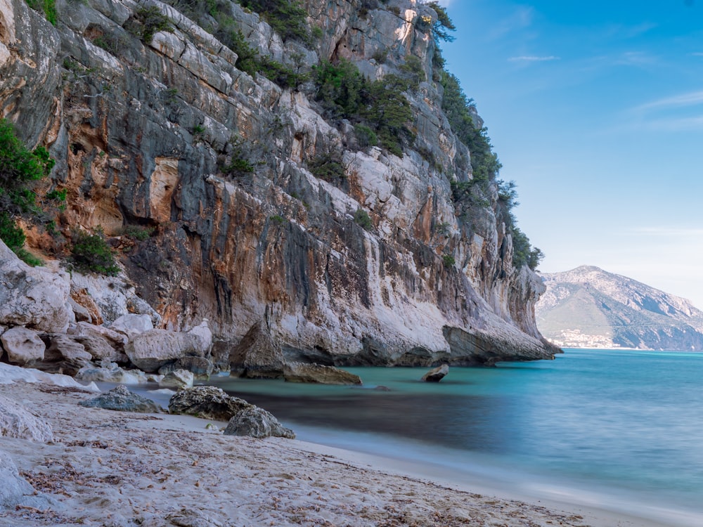 a sandy beach next to a rocky cliff