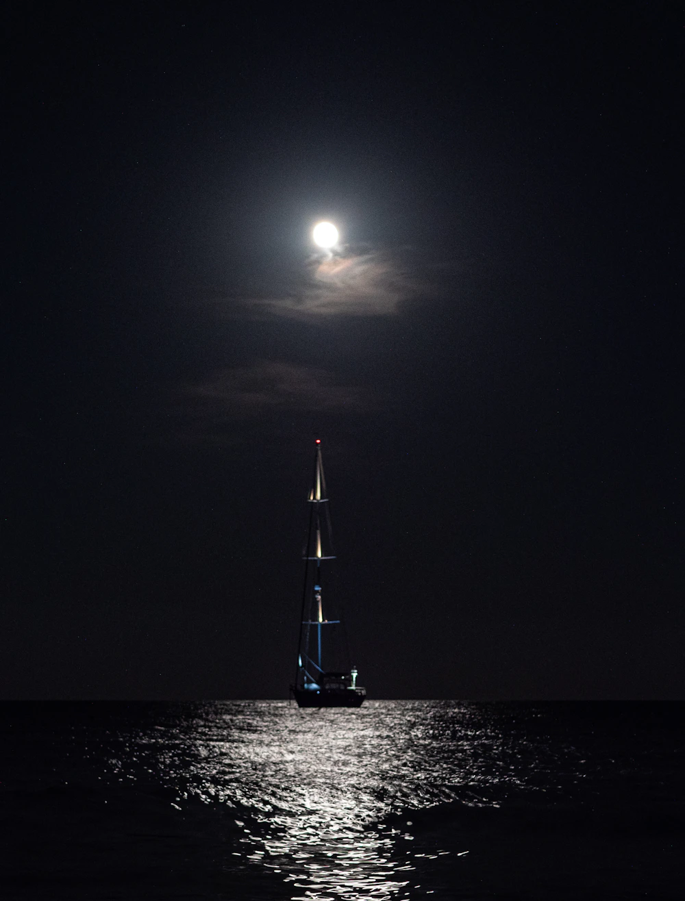 Velero sobre el agua bajo una luna llena