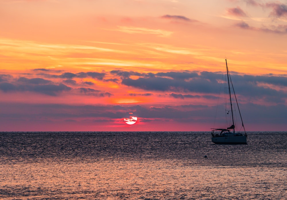 a sailboat in the ocean at sunset